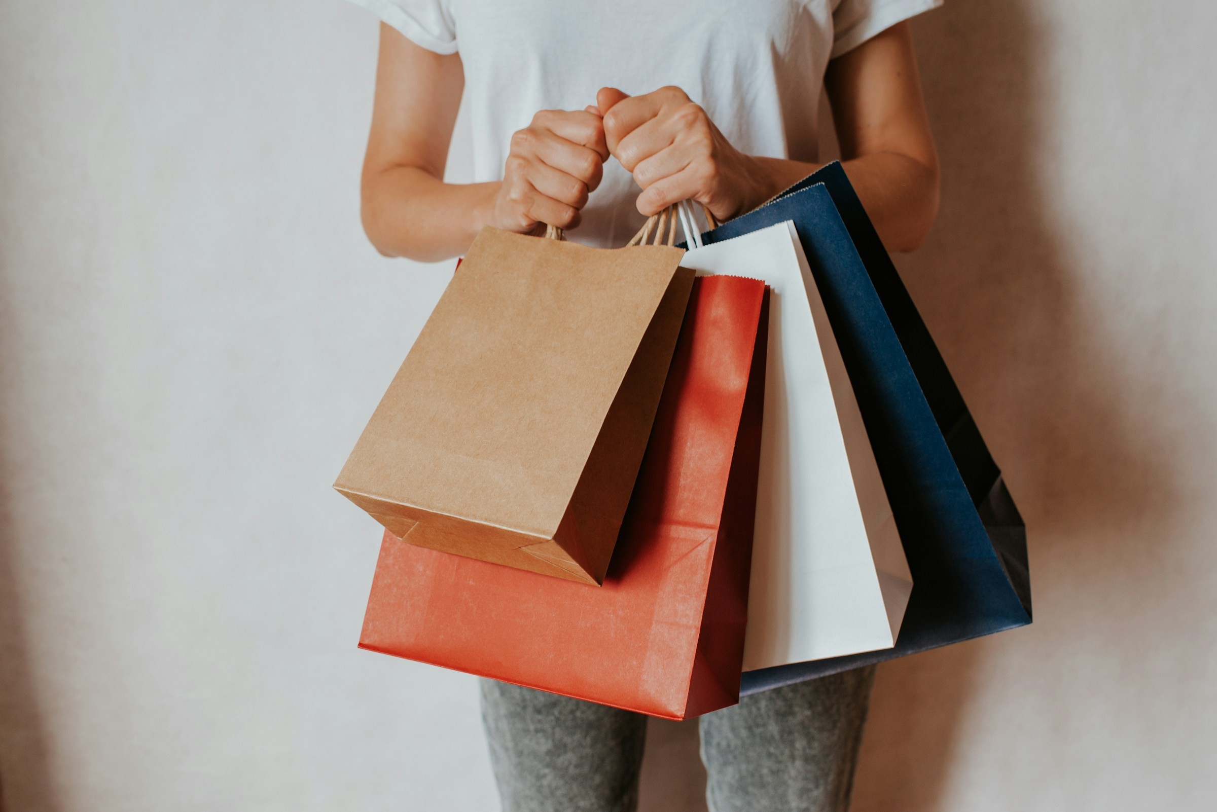 A shopper holding a bundle of colorful paper shopping bags
